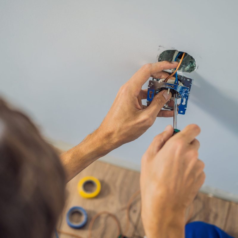 Master electrician installs a socket in the house.